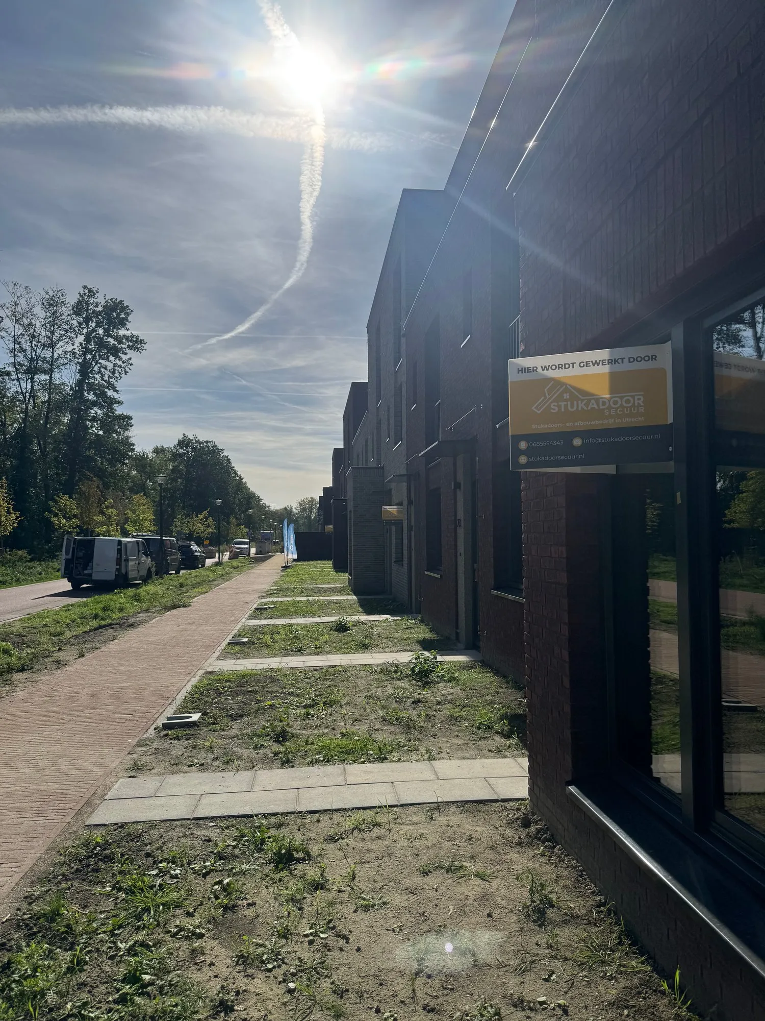 Bouwbord ‘Hier wordt gewerkt door Stukadoor Secuur’ aan een rij nieuwbouwwoningen