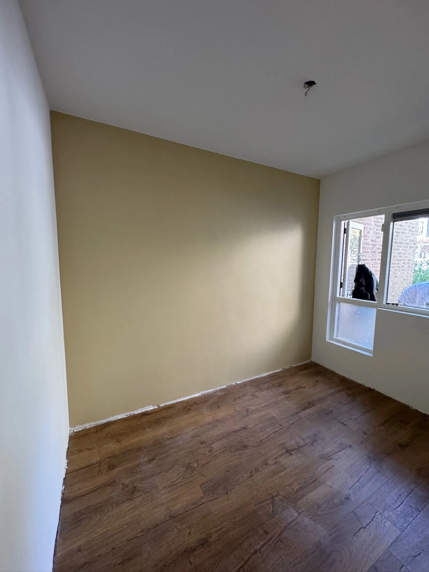 Dezelfde kamer gesausd, met een accentwand in een warme tint