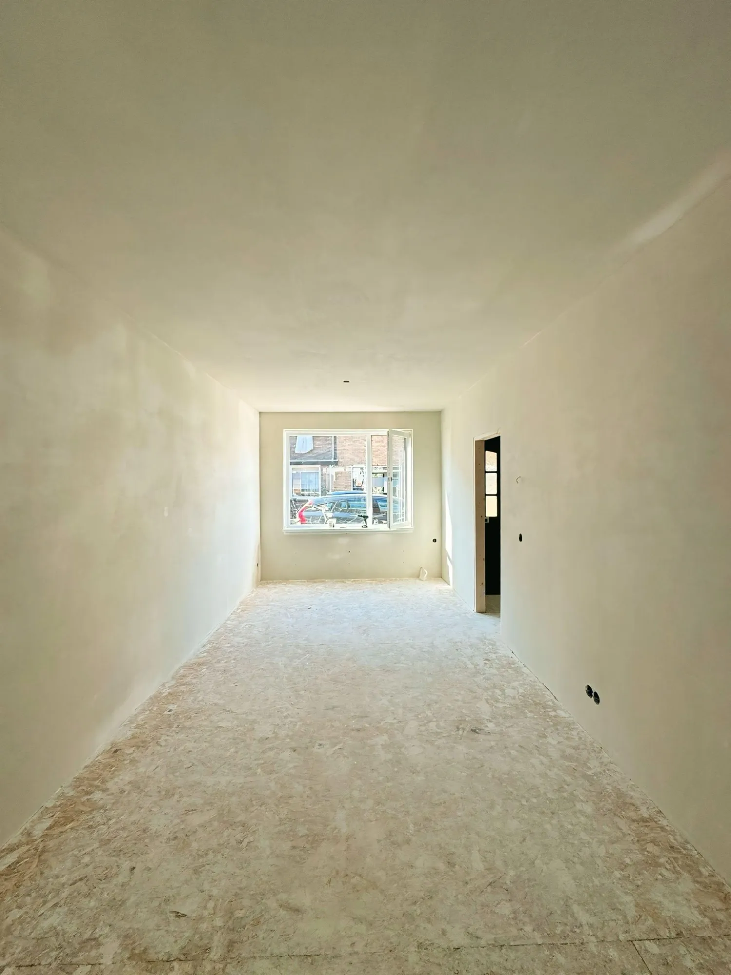Dezelfde woonkamer met strak glad gestucte wanden en plafond